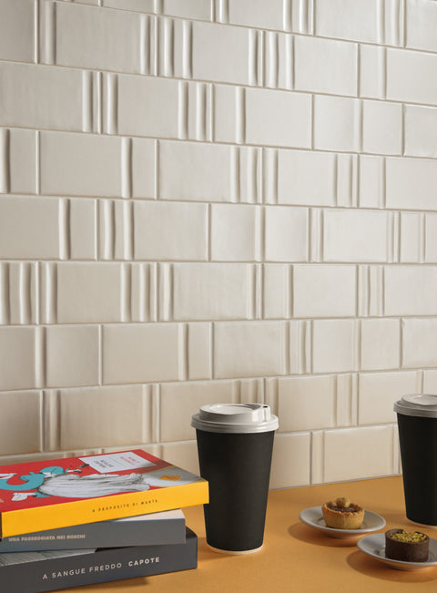 Track Alabaster Decor Mix — warm ivory relief tiles in a cafe setting