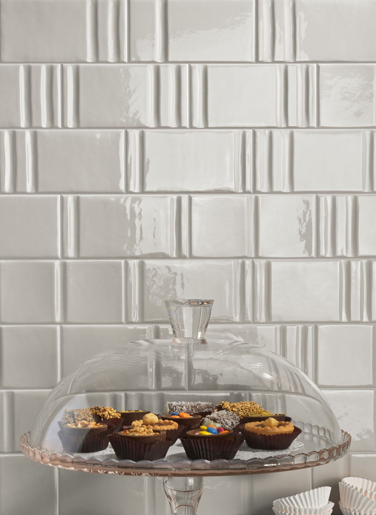 Track Pewter Decor Mix — grey sculpted tiles behind glass cake stand